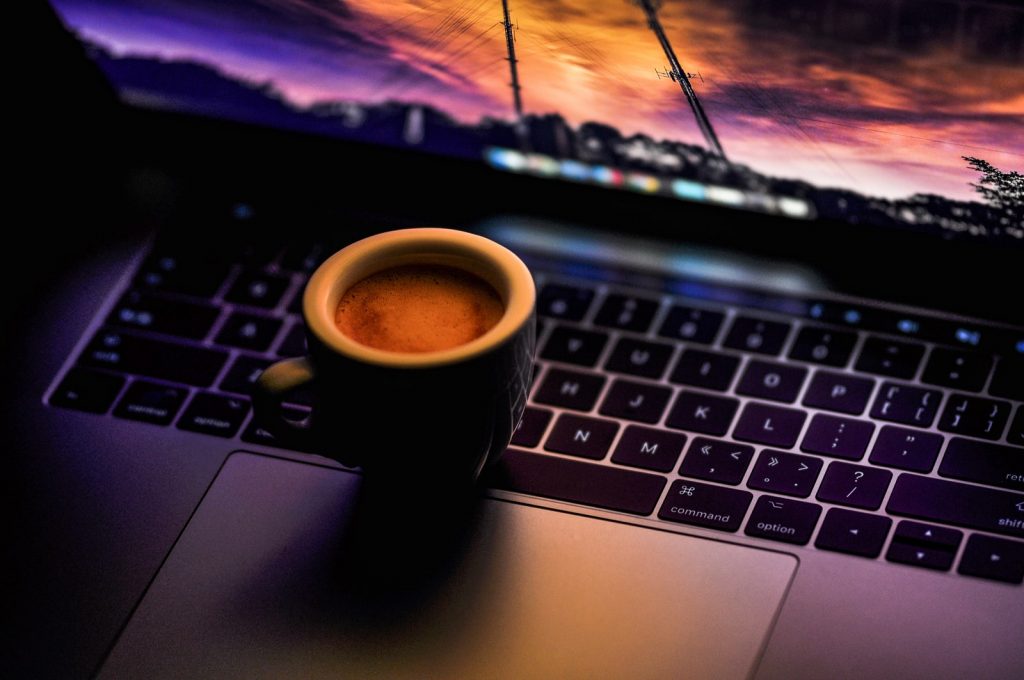 black ceramic coffee mug on MacBook Pro at night